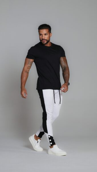 Calça Preta Com Branco, Com Recortes, Botões Na Barra E Acessórios Brancos.